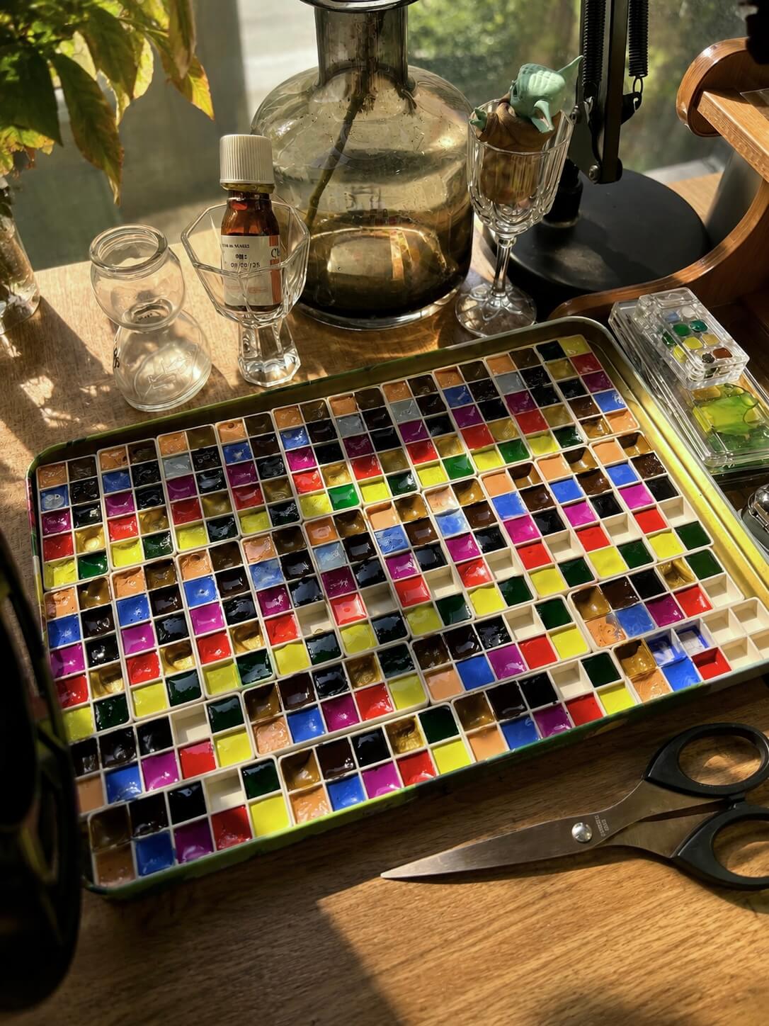 Palette tin packed with colourful watercolour pans in golden light