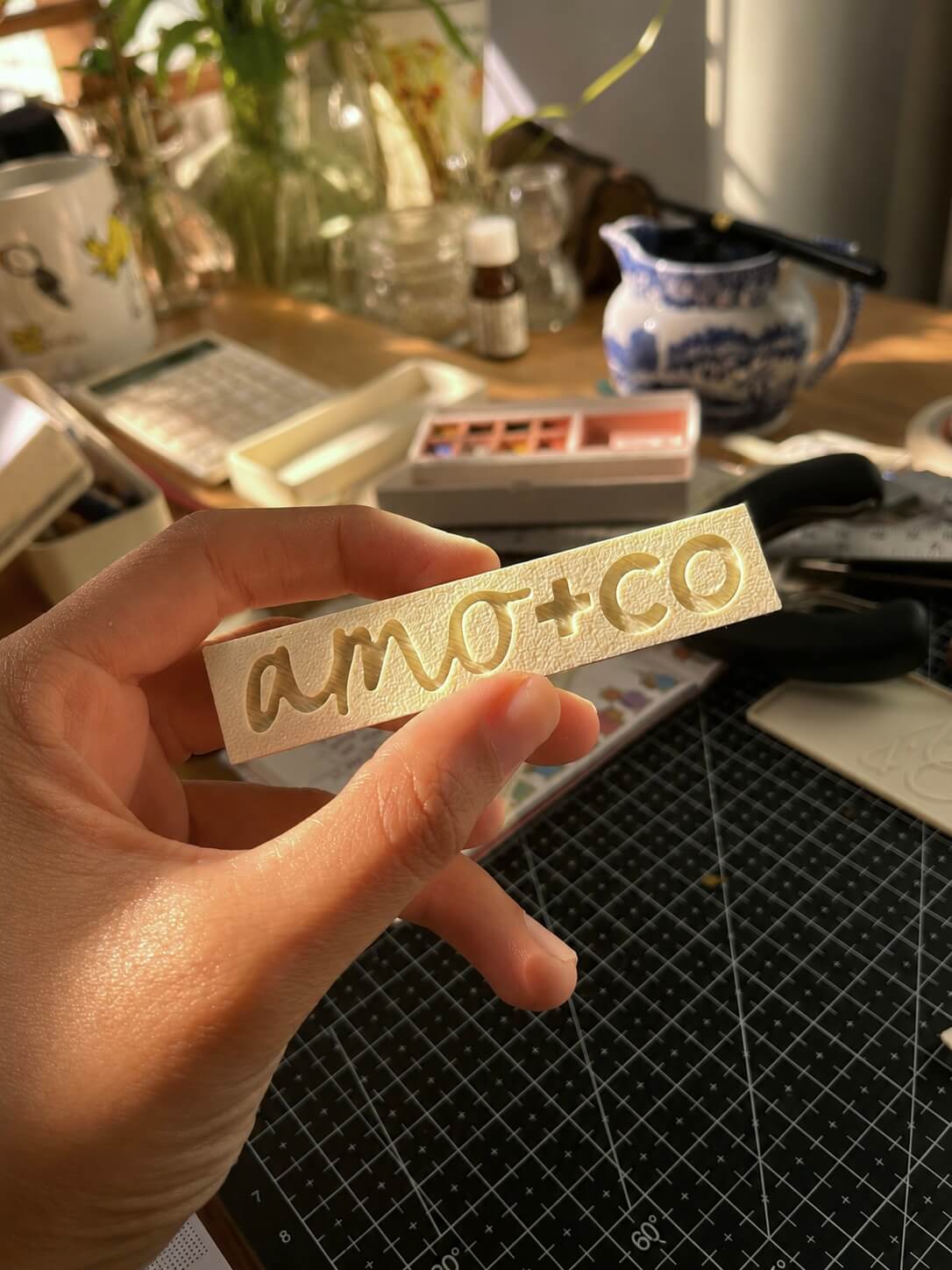 amo+co clay stamp held up in warm studio light
