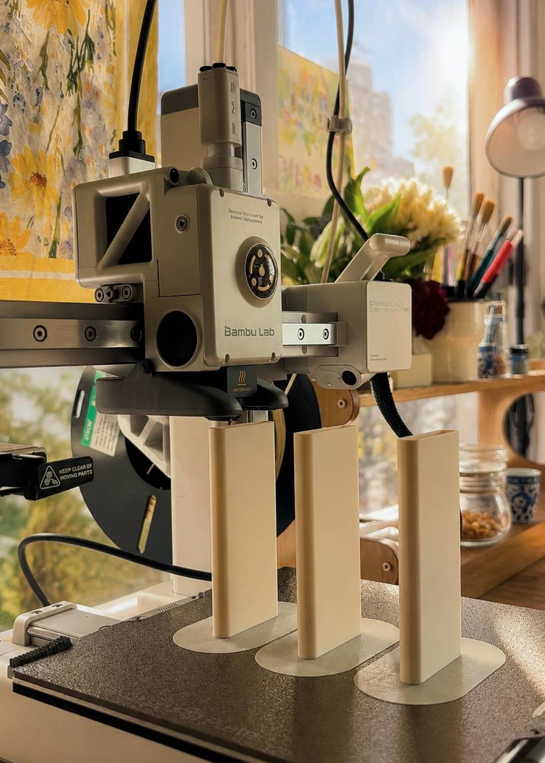 Bambu Lab 3D printer printing cream pen holders in the studio