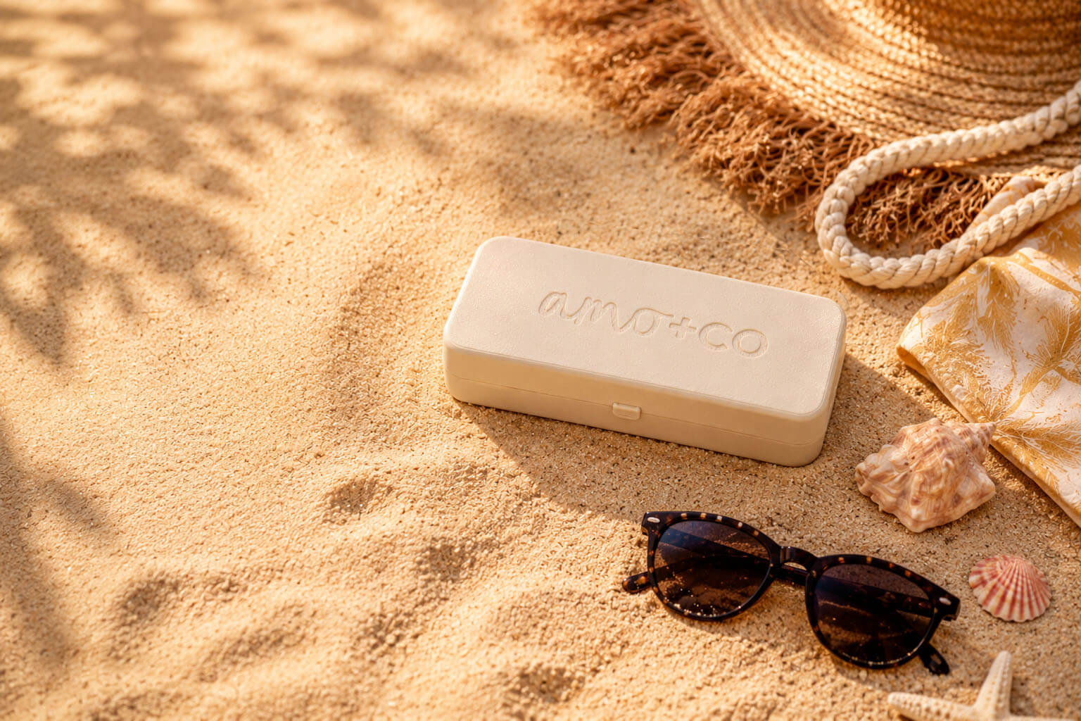 amo+co palette on golden sand with sunglasses, shells, and beach essentials